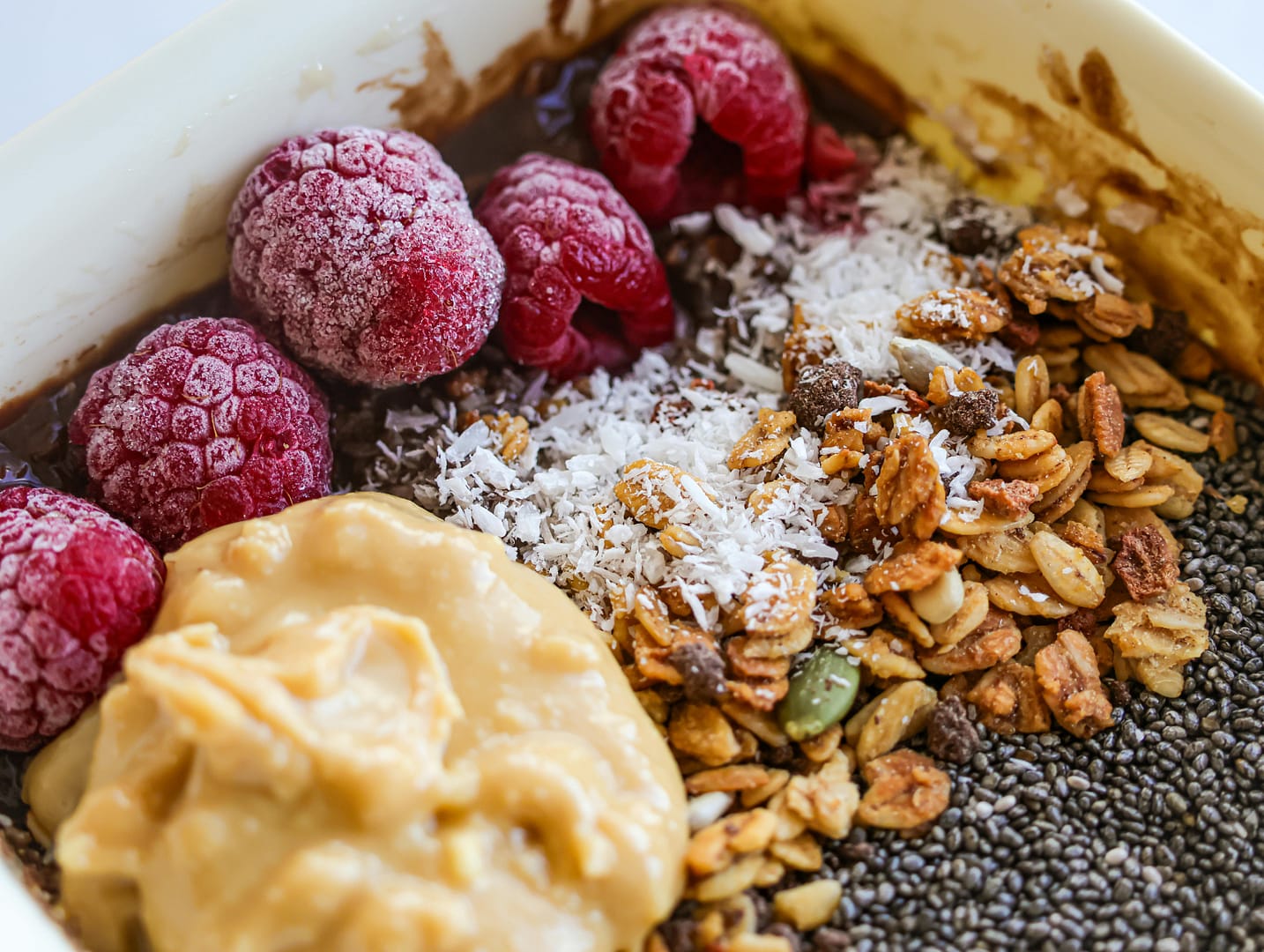 A beautifully arranged plate of plant-based energy bites with a mix of nuts, seeds, and dried fruit, placed on a rustic wooden surface. The scene has warm, natural lighting, highlighting the texture and wholesome ingredients of the healthy snack.