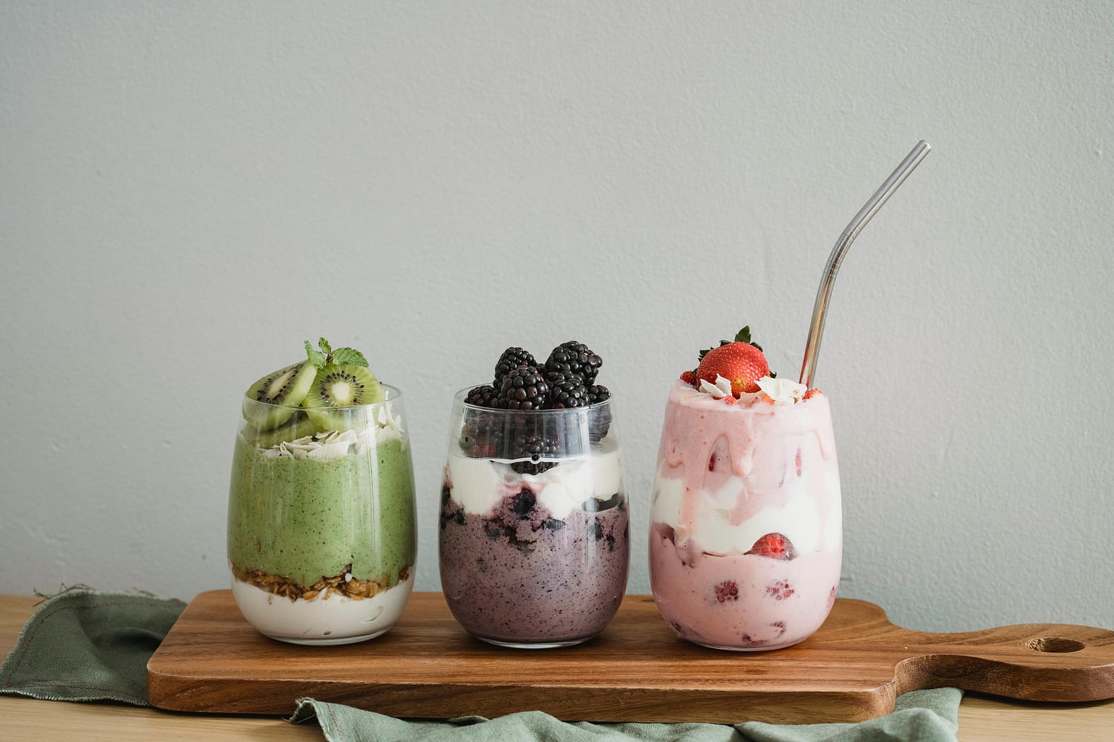 Fresh Fruit & Yogurt Smoothies Recipes: Three vibrant smoothies made with fresh strawberries, kiwi, and blackberries, topped with yogurt and served in glass jars
