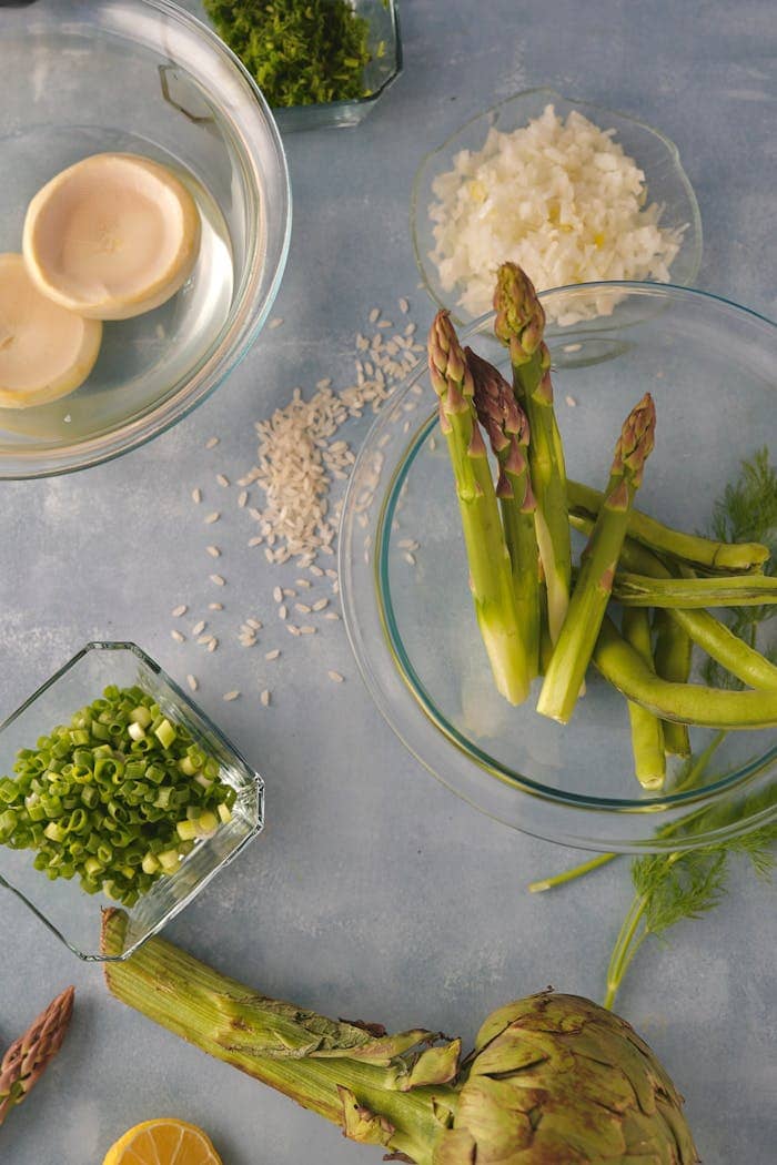 Colorful flat lay of fresh asparagus, artichoke, and ingredients on a light surface.