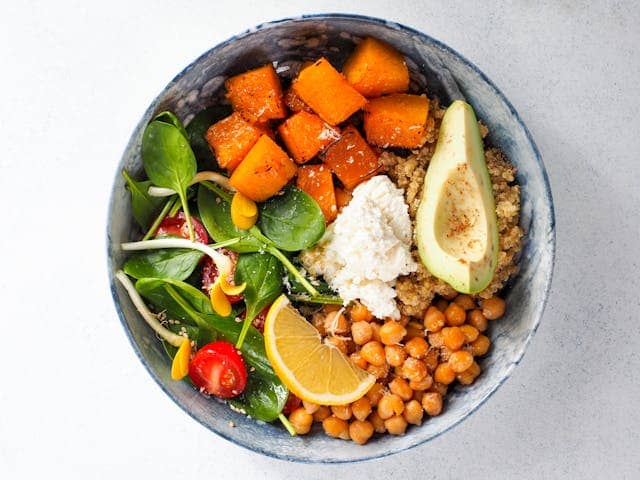 Colorful and vibrant plant-based Buddha bowl with vegetables, grains, and toppings, symbolizing nourishment and wellness."